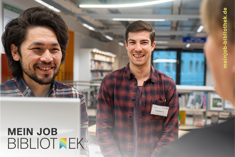 Zwei junge Männder stehen in einer Bibliothek, sie lächeln in die Kamera. Links unten das Logo Mein Job Bibliothek